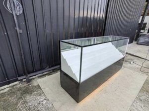 Glass Retail Display Counter with White Tiered Shelves, LED Lighting, and a Glossy Black Base