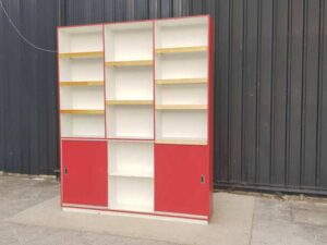 Wooden shelving unit with 2 sliding doors and 13 compartments, white and red.