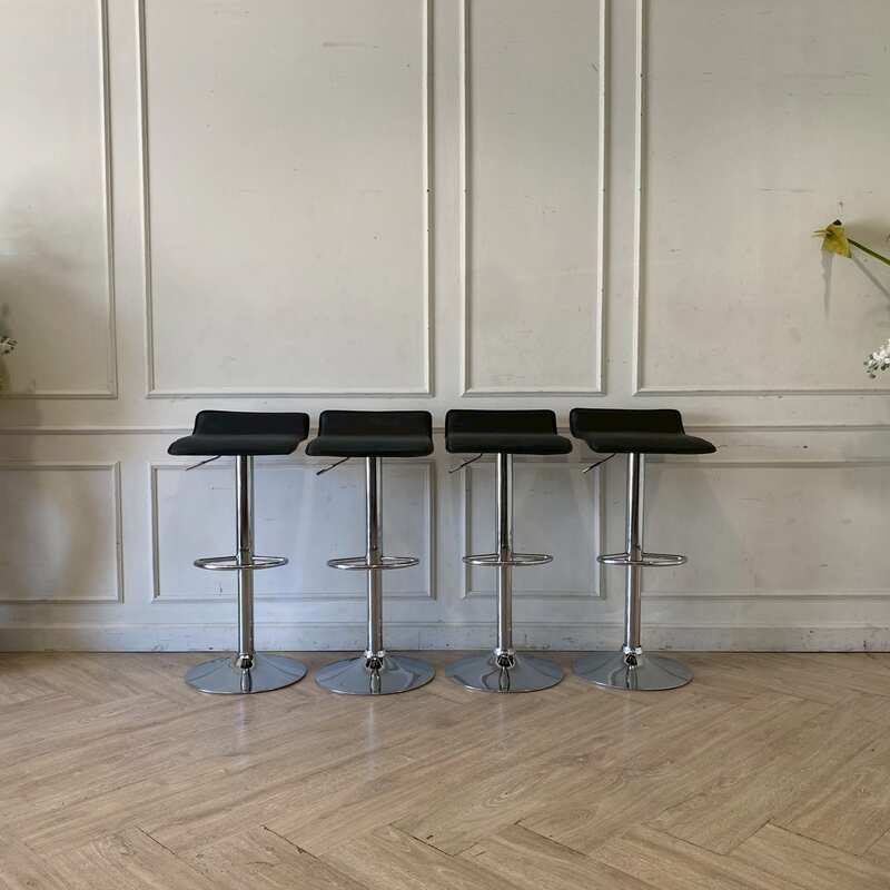 Bar stool with steel legs and black leather seat.