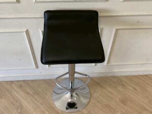 Bar stool with steel legs and black leather seat.