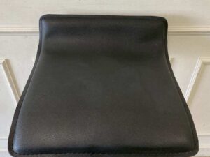 Bar stool with steel legs and black leather seat.