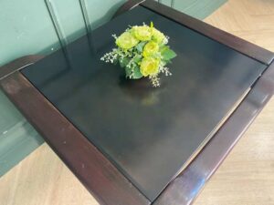 Wooden coffee table with glass top, solid gray color.