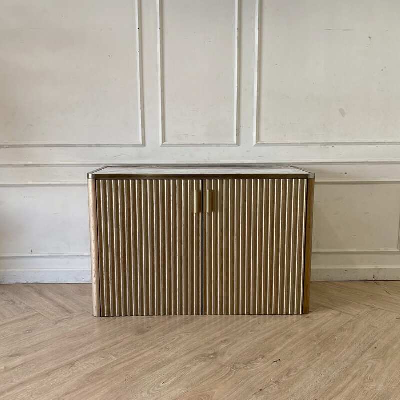 A rectangular, modern luxury wooden cabinet with two doors, in brown with gold stainless steel trim.