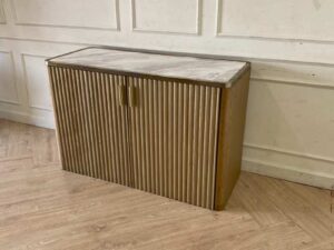 A rectangular, modern luxury wooden cabinet with two doors, in brown with gold stainless steel trim.