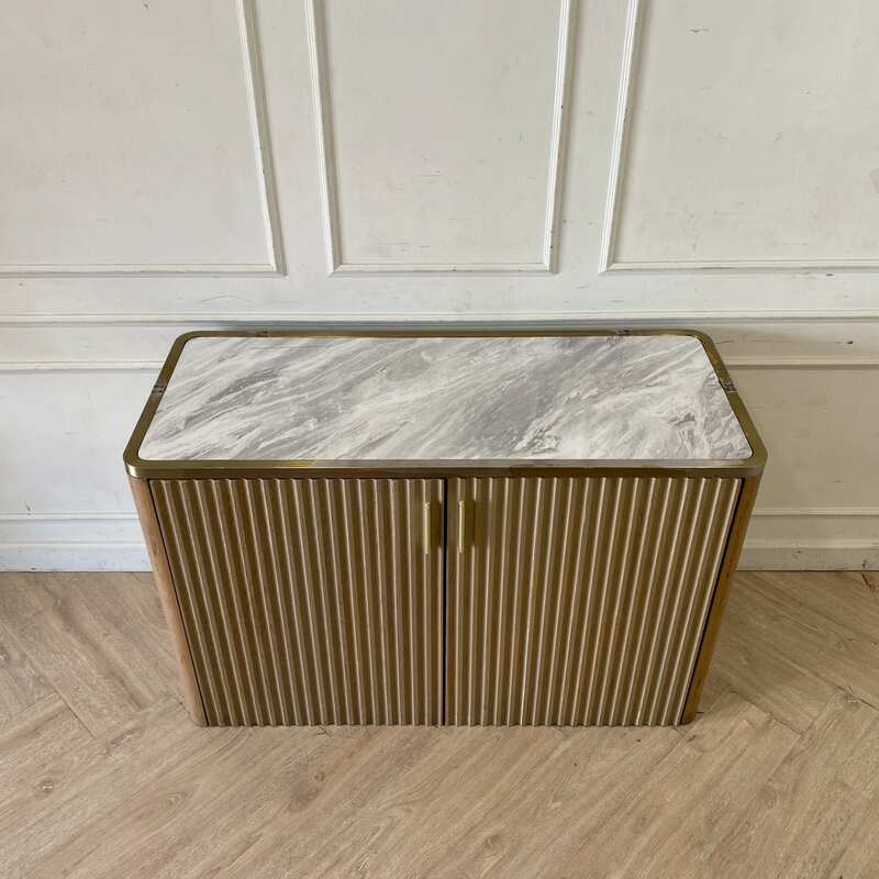 A rectangular, modern luxury wooden cabinet with two doors, in brown with gold stainless steel trim.