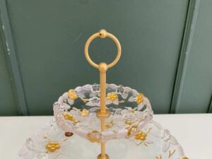 Two-tiered glass dessert and fruit stand with floral design and gold rim, European style.