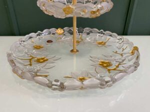 Two-tiered glass dessert and fruit stand with floral design and gold rim, European style.