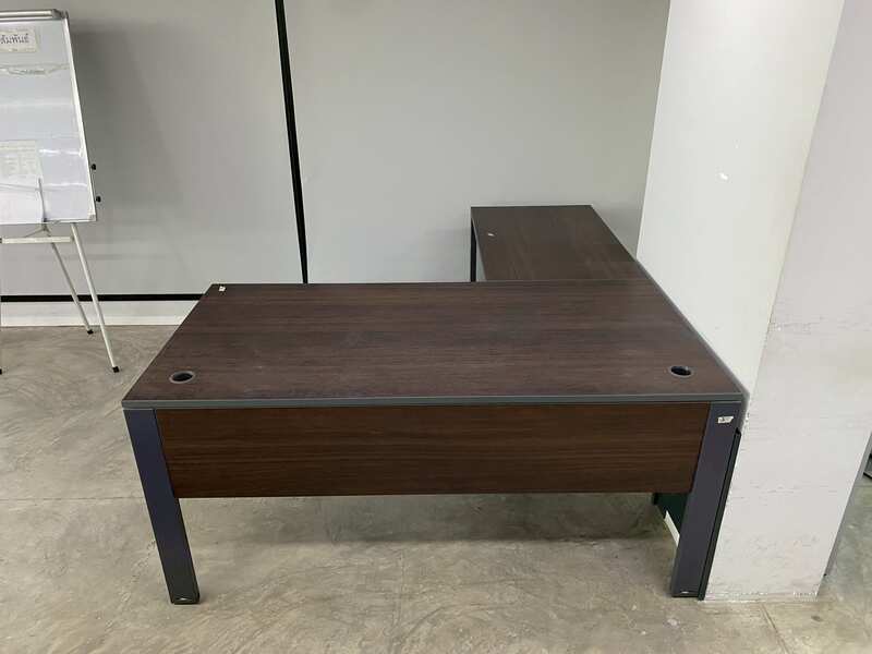 L-shaped corner desk with steel legs and dark brown wood top, with power strip.