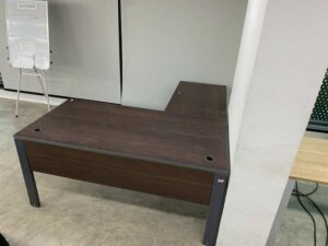 L-shaped corner desk with steel legs and dark brown wood top, with power strip.