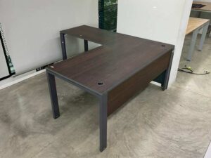 L-shaped corner desk with steel legs and dark brown wood top, with power strip.