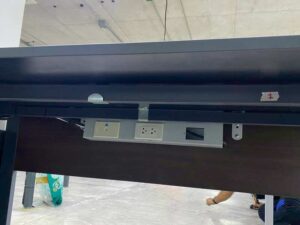 L-shaped corner desk with steel legs and dark brown wood top, with power strip.