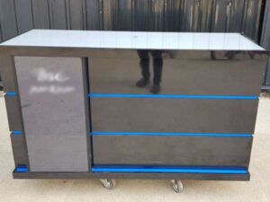 Black wooden counter with 2 sliding doors and 4 drawers.