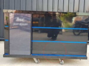 Black wooden counter with 2 sliding doors and 4 drawers.