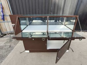 Brown glass display cabinet featuring 2 hinged-door compartments, 2 drawers, and 1 storage compartment (no keys; all sections are accessible).