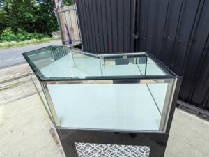 Black glass display counter featuring 3 hinged doors, 3 drawers, and 3 storage compartments.