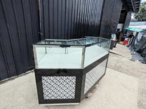 Black glass display counter featuring 3 hinged doors, 3 drawers, and 3 storage compartments.