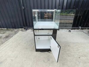 Tall glass display cabinet with one storage compartment; no drawers.