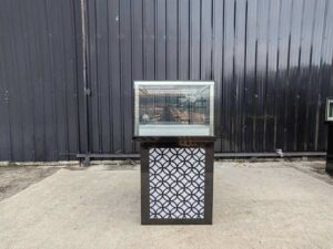Tall glass display cabinet with one storage compartment; no drawers.