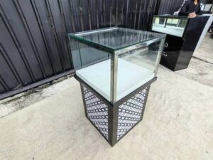 Tall glass display cabinet with one storage compartment; no drawers.