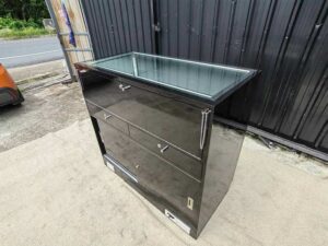 Black glass display cabinet featuring one hinged door, two drawers, and one sliding-door storage compartment.