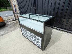Black glass display cabinet featuring one hinged door, two drawers, and one sliding-door storage compartment.