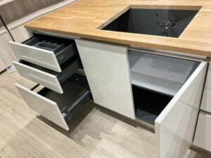 White built-in unit with wooden countertop, overhead cabinets, and refrigerator alcove (1)